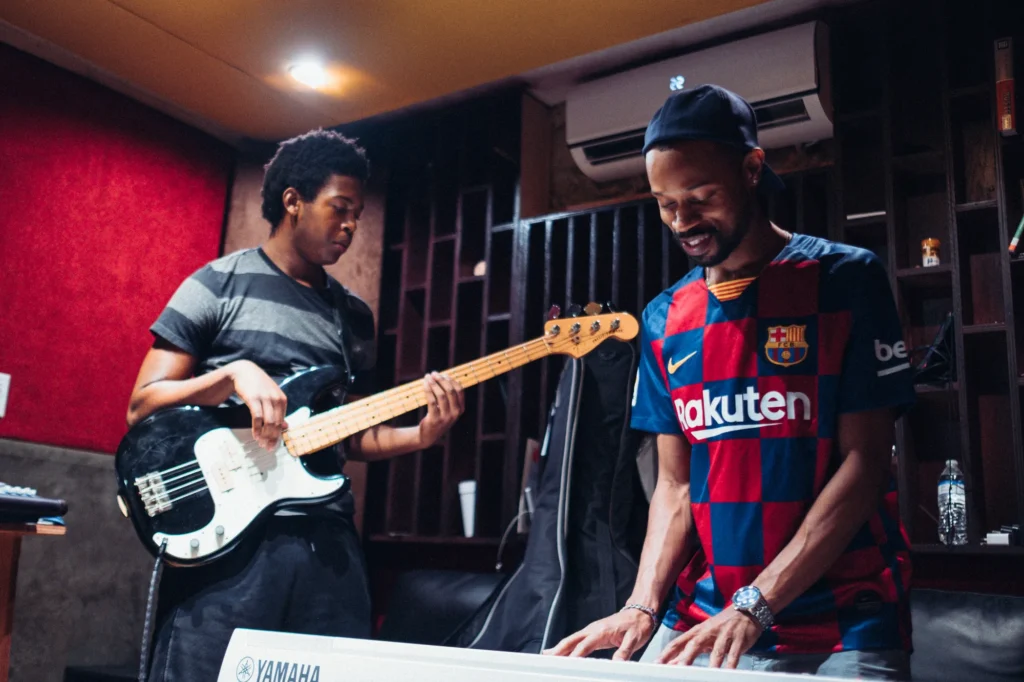 Two musicians playing bass and keyboard during a studio session in Miami