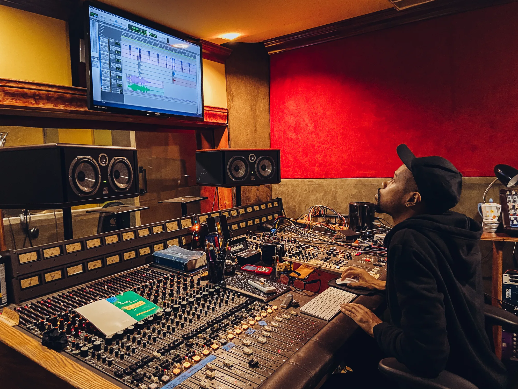 Musician at a studio mixing console with monitors and recording equipment